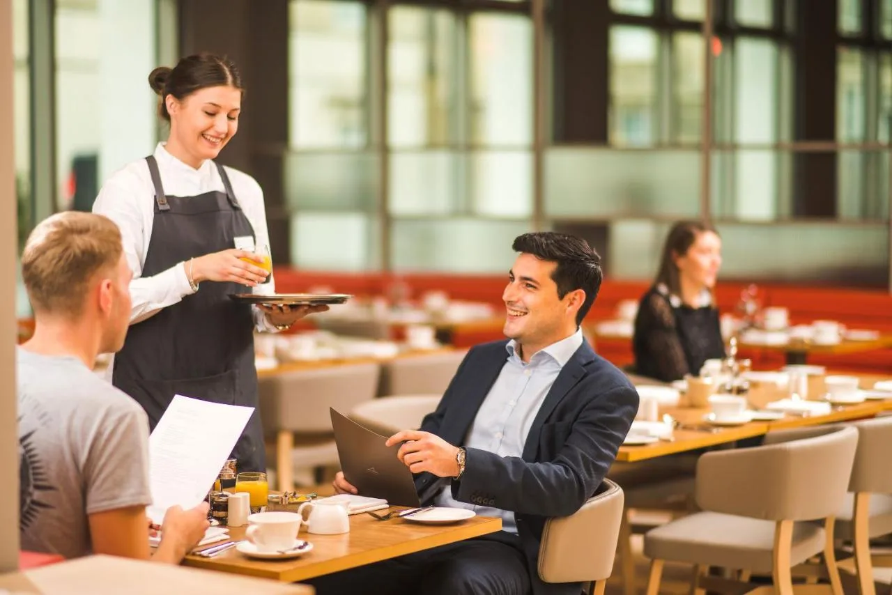 a waitress serving people in a restaurant at Apex City of Bath Hotel in Bath