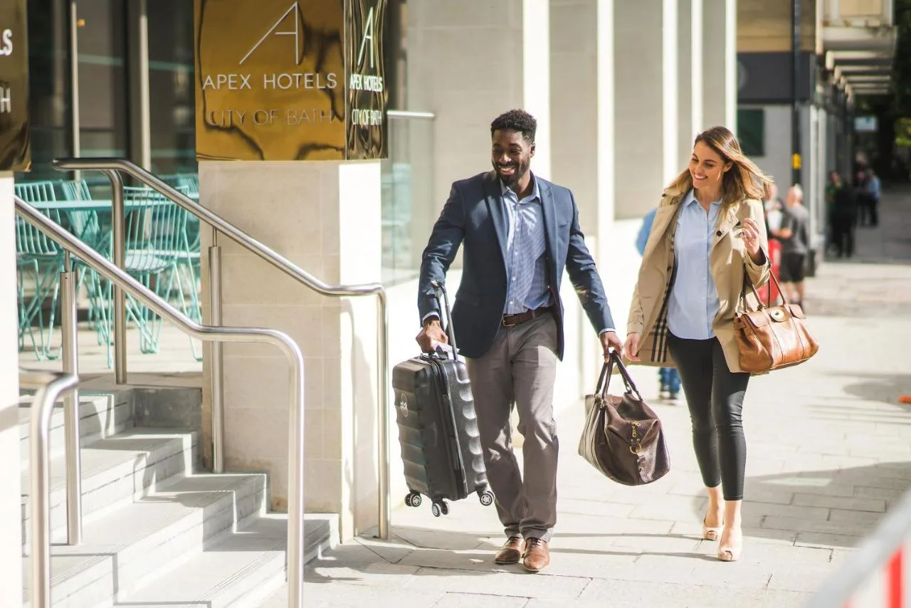 a man and a woman walking down a street with luggage at Apex City of Bath Hotel in Bath